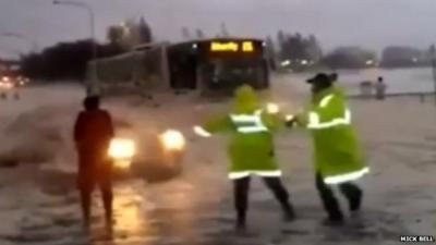 Car emerging from foam with two people with florescent jackets in front