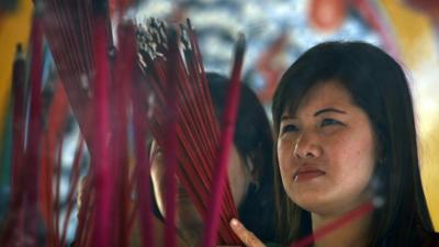 An Indonesian ethnic Chinese woman holds incense sticks during Lunar New Year celebrations at a temple in Jakarta, Indonesia