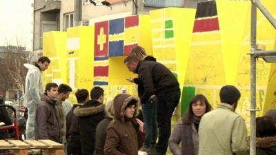 People painting flags on sculpture