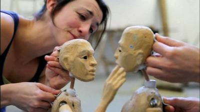 Actors rehearse with two wooden puppets