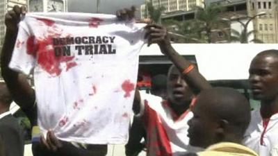 Supporters of Raila Odinga holding up T-shirt saying "democracy on trial"