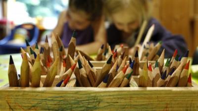 Colour pencils are pictured as children draw at a nursery school