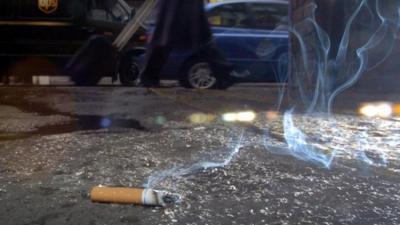 Cigarette left smoking on a pavement