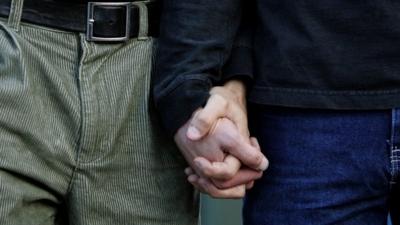 Two men hold hands