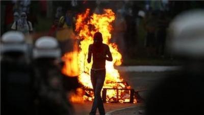 A protester walks in front of a burning barricade in Salvador