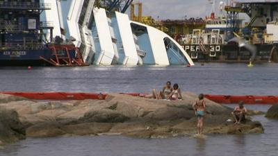 People in sea with Costa Concordia in the background