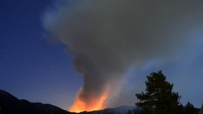 A plume of smoke rises into the night sky in southern California