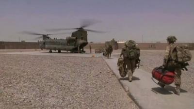 British troops carry bags to an Apache helicopter