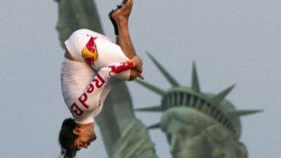 Orlando Duque performs a 75-foot tuck dive from a helicopter, beside the Statue of Liberty in New York.