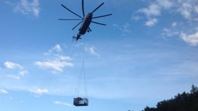 Helicopter lifting bear in a cage from a flooded area in Russia.