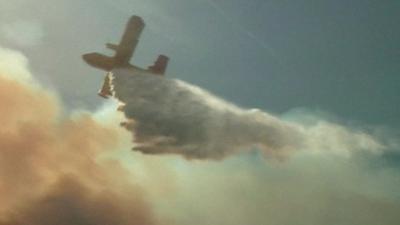 A water-bombing plane flying over a wildfire