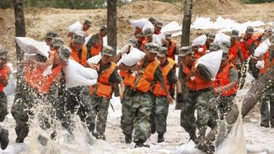 Soldiers rush to set up sand bags to prevent flood from an overflowing river in Heihe, Heilongjiang province, China