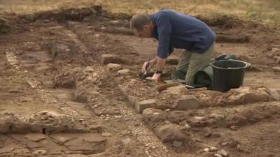 A volunteer works on excavating the training trench