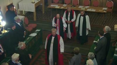 Four male bishops inside a Church