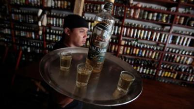 A waiter serves a bottle of cachaca, Brazil's national spirit