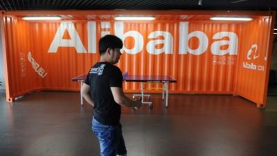 Employee walks past Alibaba sign