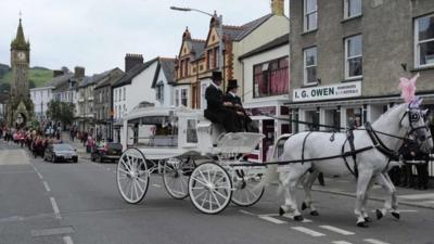 The coffin of April Jones is carried by a horse-drawn carriage