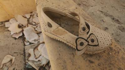 A child's shoe with burnt books and papers on the ground