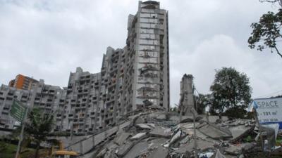 Rescue workers look at the remains of a building that collapsed late Saturday, in Medellin, Colombia