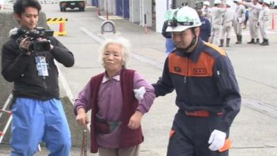 Elderly woman is helped to a boat