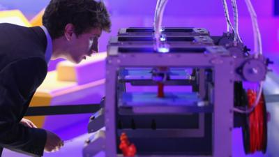 A man looking at a 3D printer