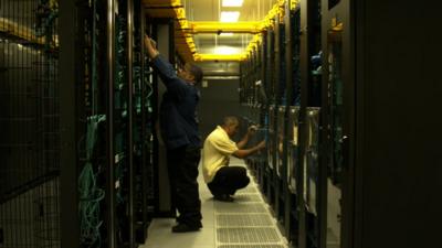 Two men work with computer servers