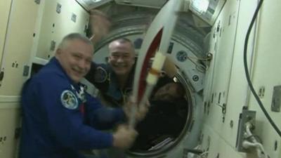 Cosmonauts and astronaut with Sochi torch on board the ISS