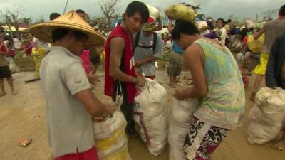 Survivors of Typhoon Haiyan with bags of food