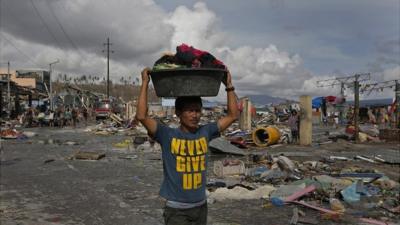 A man carrying goods through the disaster zone at Tacloban, in the Philippines