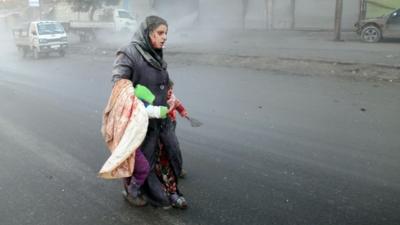 A wounded Syrian woman walks with her children following airstrikes on a rebel area of the war-torn northern city of Aleppo, 15 December 2013