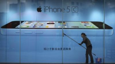 Worker cleaning in front of an iPhone 5C advertisement