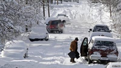 A man clears snow from his car in Indianapolis, Indiana January 6, 2014