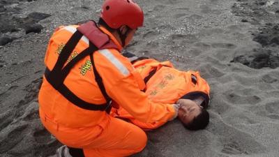 A Taiwanese Coast Guard treats Tseng Lien-fa after he was rescued from the sea