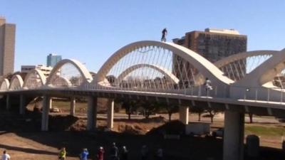 Biker rides along the top of a curved bridge