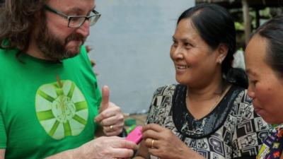 Hairy biker Dave Myers hands pink mobile phone to woman