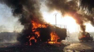 A Syrian man (left) runs next of a burned truck that was attacked by a Syrian forces helicopter in Aleppo (18 January 2014)