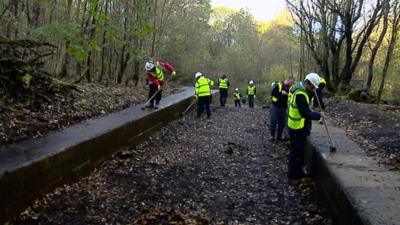 People clearing a disused canal lock