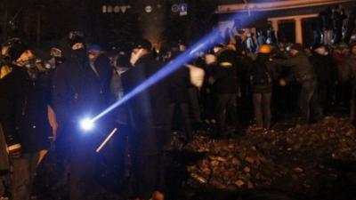 Anti-government protester uses a flashlight during a rally in Kiev