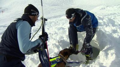 Two mountain gendarmes train a rescue dog on the snowy slopes above the village of Montgenèvre