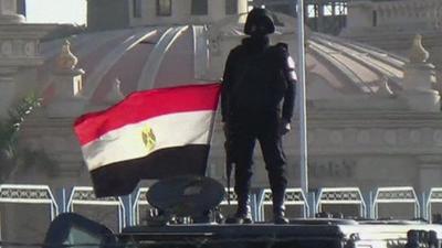 Egyptian police officer stands on armoured vehicle