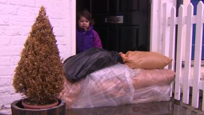 Child standing at door next to sandbags