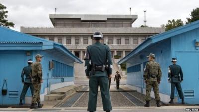 South Korean soldiers look towards the North Korean side as a North Korean solder approaches the UN truce village building that sits on the border of the Demilitarized Zone (DMZ) in Panmunjom, South Korea, on 30 September 2013