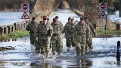 Members of The King's Royal Hussars wade through flood water on Chertsey Meads