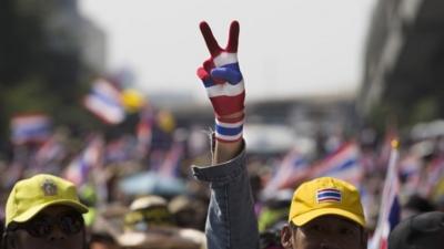 An anti-government protester from the People's Democratic Reform Committee flashes a peace sign during a march in Bangkok on 18 January 2014