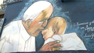 A mural featuring Pope Francis kissing a baby