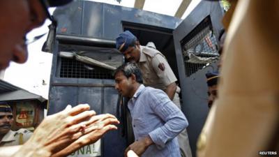 People escort one of the accused men to court