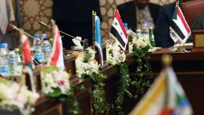 A Syrian flag (C) is displayed next to the empty Syrian seat during the opening session of the Arab League Foreign Ministers' meeting in Kuwait City on March 23