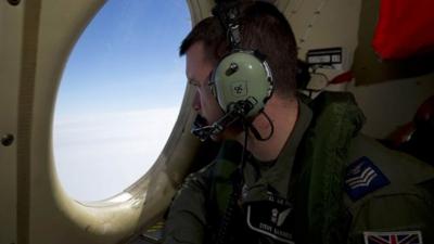 Royal Air Force Sergeant Steve Barnes looks out of an observation window on a Royal Australian Air Force