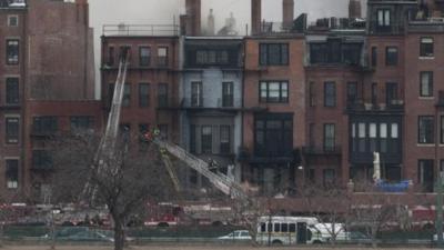 Smoke rises from across the Charles River above buildings on Beacon Street in Boston's Back Bay neighborhood