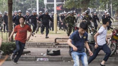 People run as riot police officers try to disperse protesters